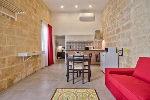 a living room with a red couch and a kitchen at Vallettastay Old Lodge Apartment 3 in Valletta