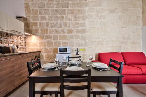 a dining room with a table and a red couch at Vallettastay Old Lodge Apartment 3 in Valletta
