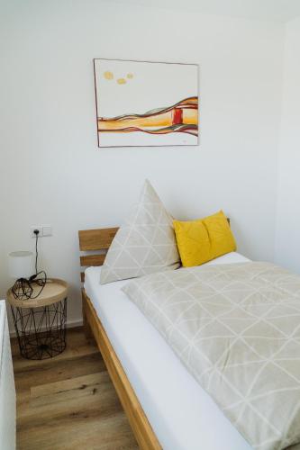 a bedroom with a white bed with a yellow pillow at Wohnen auf Zeit in Weingarten in Weingarten