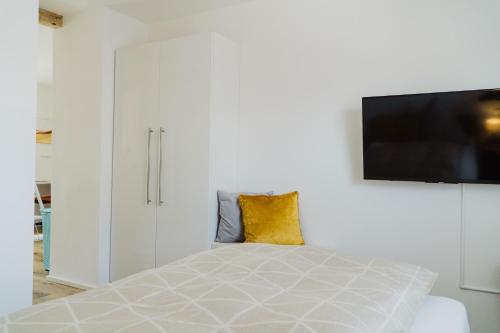 a white bedroom with a bed and a tv on a wall at Wohnen auf Zeit in Weingarten in Weingarten