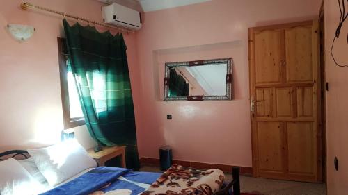 a bedroom with a bed and a mirror and a window at Hôtel Restaurant BOUGAFER in Oulad Akkou