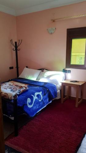 a bedroom with a bed and a table with a window at Hôtel Restaurant BOUGAFER in Oulad Akkou