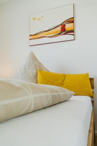 a bed with yellow pillows and a painting on the wall at Wohnen auf Zeit in Weingarten in Weingarten