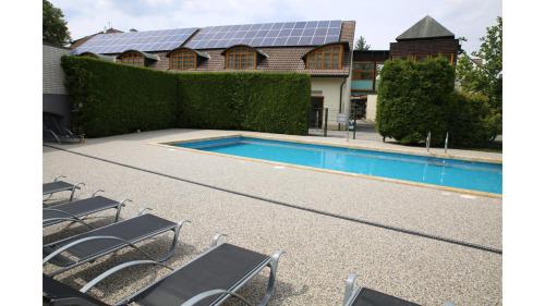 a swimming pool with chairs and a house with a solarium at Hotel Baroko in Prague