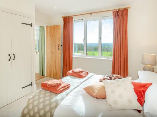 - une chambre avec un lit doté d'oreillers et d'une fenêtre dans l'établissement Windover Barn, à Slinfold