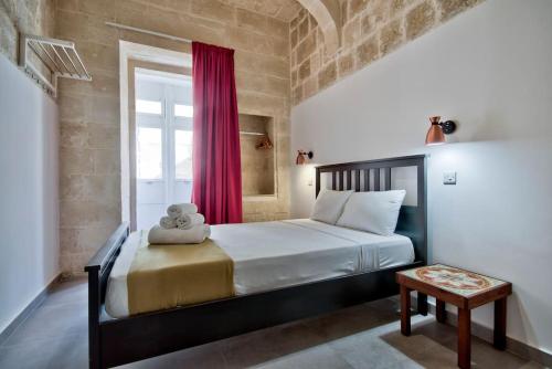 a bedroom with a large bed with a red curtain at Vallettastay Old Lodge Apartment 4 in Valletta