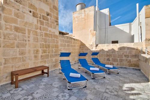 a row of blue chairs sitting next to a wall at Vallettastay Old Lodge Apartment 4 in Valletta
