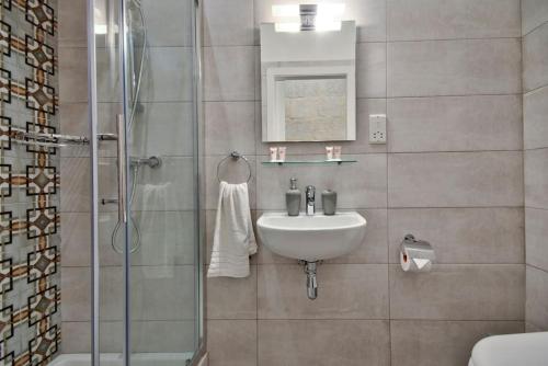 a bathroom with a sink and a shower at Vallettastay Old Lodge Apartment 4 in Valletta