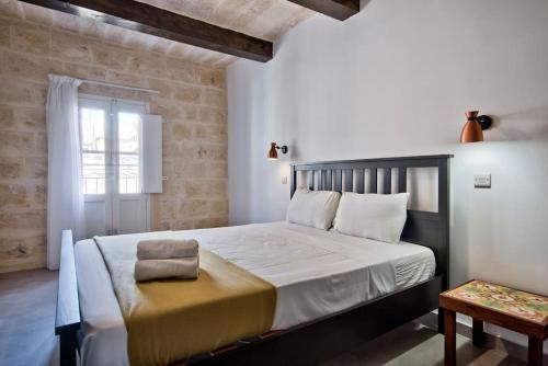a bedroom with a large bed and a window at Vallettastay Old Lodge Apartment 7 in Valletta