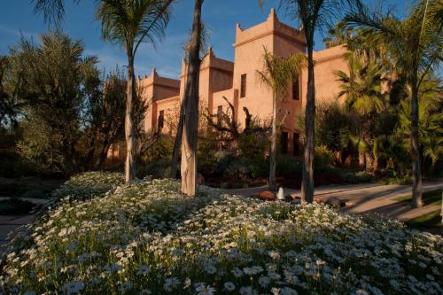 a house with palm trees and flowers in front of it at Tigmiza Boutique Hotel & Spa in Marrakech