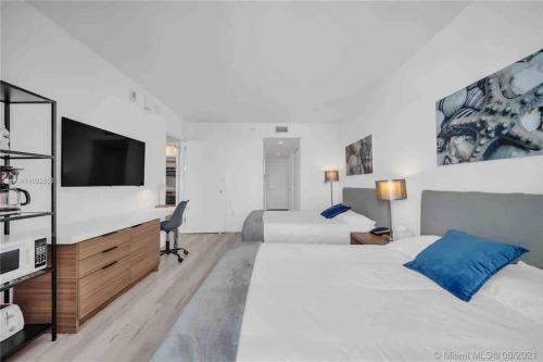 a bedroom with two beds and a flat screen tv at Relax by the Sea in This Cozy Beachfront Room 908B in Hallandale Beach