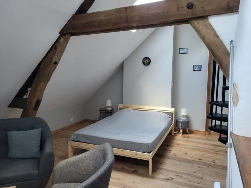 ein Schlafzimmer mit einem Bett und zwei Stühlen im Dachgeschoss in der Unterkunft La petite maison in Saint-Aignan