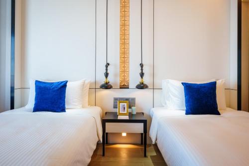 two beds with blue pillows in a room at Somerset Pattaya in Pattaya Central