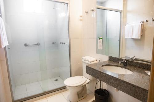 a bathroom with a shower and a toilet and a sink at Master Cosmopolitan Moinhos de Vento in Porto Alegre