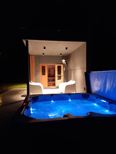 a jacuzzi tub with two white chairs in a room at Le Lièvre Debout Francorchamps - spa et sauna in Francorchamps