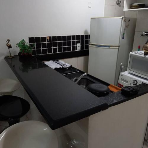 cocina con encimera negra y nevera en Luxo sala e quarto quadra da praia Copacabana, en Río de Janeiro