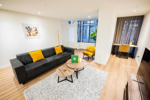 a living room with a black couch and yellow pillows at Great 95m2 Two-Bedroom Apartment - WE39 in Tiel