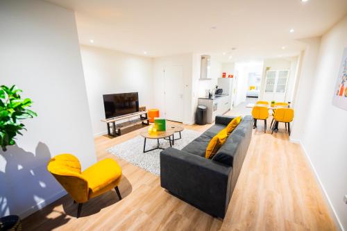 a living room with a couch and yellow chairs at Great 95m2 Two-Bedroom Apartment - WE39 in Tiel