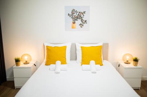 een slaapkamer met een wit bed met gele kussens bij Great 95m² Two-Bedroom Apartment in Tiel