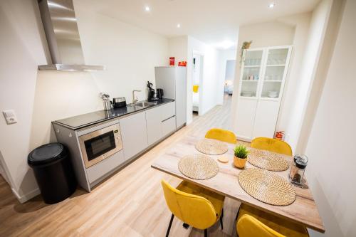 a kitchen with a wooden table and yellow chairs at Great 95m2 Two-Bedroom Apartment - WE39 in Tiel