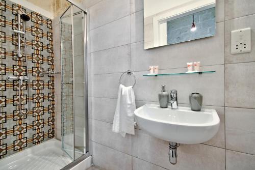 La salle de bains blanche est pourvue d'un lavabo et d'une douche. dans l'établissement Vallettastay Old Lodge Apartment 6, à La Valette