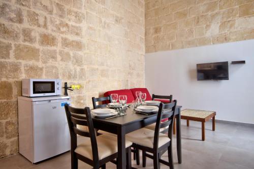 - une salle à manger avec une table, des chaises et un four micro-ondes dans l'établissement Vallettastay Old Lodge Apartment 6, à La Valette