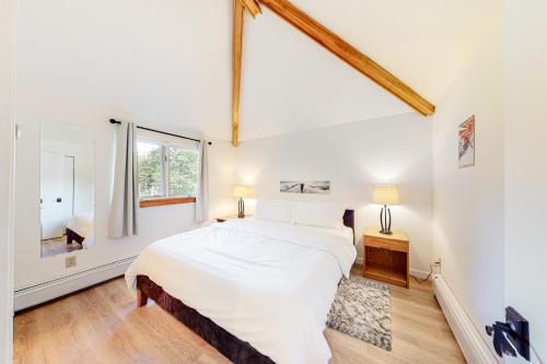 a white bedroom with a large bed and a window at The Woods Village 1 in Killington