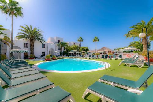 a pool with chaise lounge chairs and palm trees at Nazaret Sol in Costa Teguise