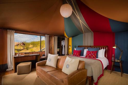 ein Schlafzimmer mit einem Bett, einem Sofa und einem Fenster in der Unterkunft Mahali Mzuri in Aitong