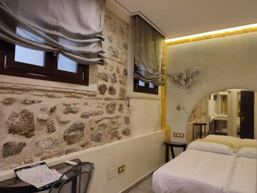 1 dormitorio con cama y pared de piedra en Grecorooms, en Toledo