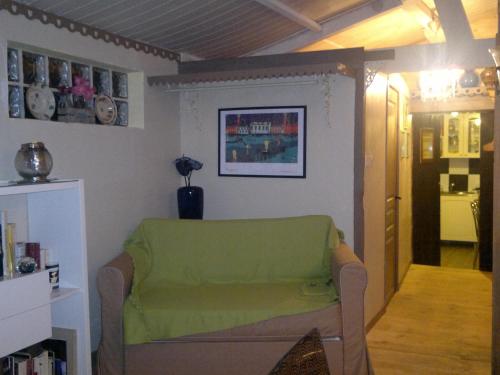 a living room with a green couch and a hallway at La Rolandière in Faverges-de-la-Tour