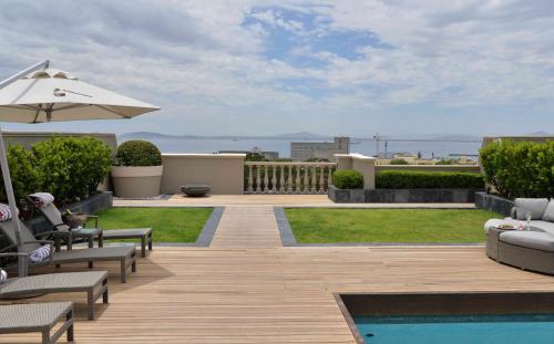 a patio with chairs and an umbrella and a pool at Cape Royale Luxury Suites in Cape Town