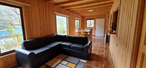 a living room with a black leather couch in a house at Bona Vista in Puerto Bertrand