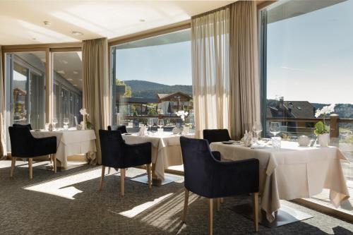 アヴェレンゴにあるHotel Chalet Mirabellのテーブルと椅子、大きな窓のあるレストラン