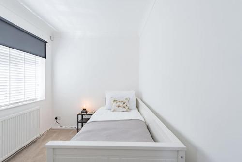a white bedroom with a bed and a window at The Heights in Kingsdown