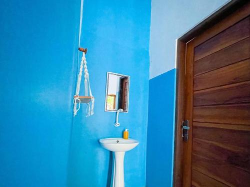 a blue bathroom with a white sink and a door at Pandan Wangi in Nusa Lembongan