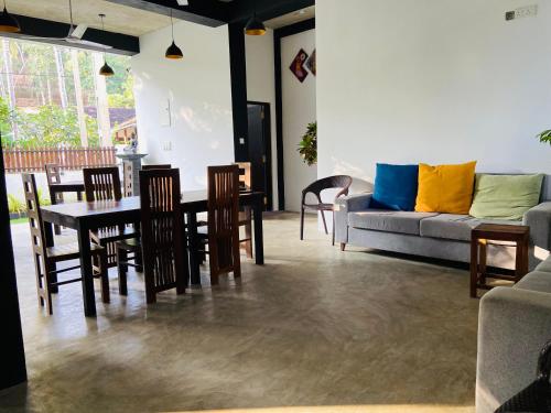 a living room with a couch and a table and chairs at Atrium Hiriketiya in Hiriketiya