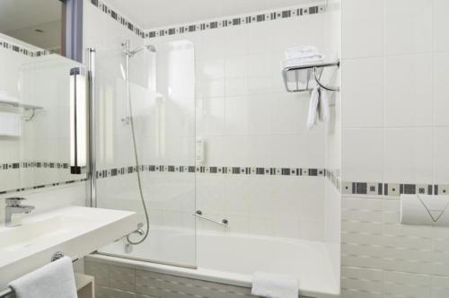 baño blanco con ducha y lavamanos en The Originals City, Hôtel du Parc, Avignon Est (Inter-Hotel) en Entraigues-sur-la-Sorgue