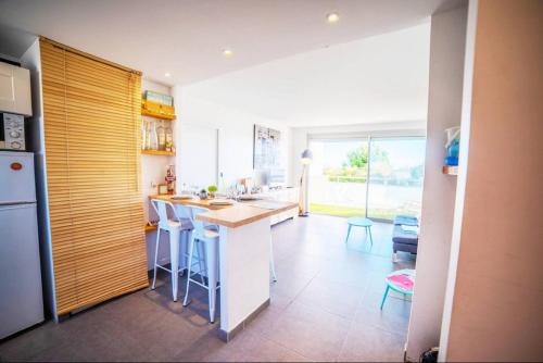 une cuisine avec des armoires blanches et un comptoir avec des tabourets dans l'établissement LE CALDERINI APPART - Face PLAGE WIFI et PARK Gratuit CALME - Résid Le Surcouf -TOP PROS SERVICESConciergerie La Grande Motte, à La Grande Motte