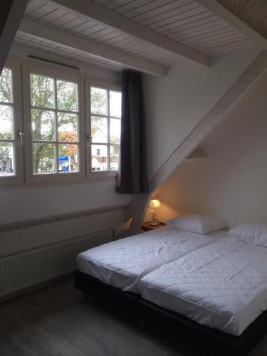a bedroom with a bed and two windows at Kerkplein Vakanties in Vrouwenpolder