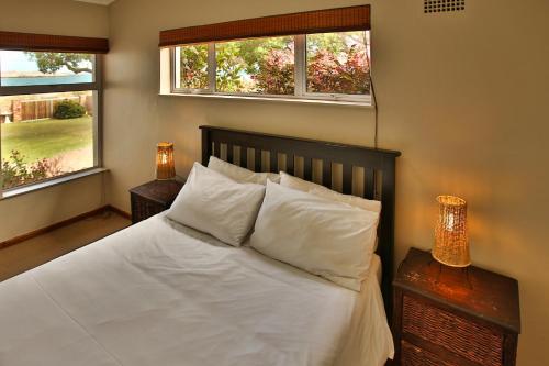 Un dormitorio con una cama blanca con dos ventanas. en Seemansrust, Langebaan, 9-sleeper, en Langebaan