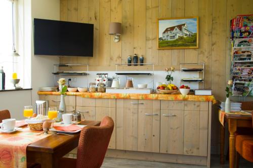 een keuken met houten kasten en een tafel en een televisie bij Wil's Bed & Breakfast in Zoutelande