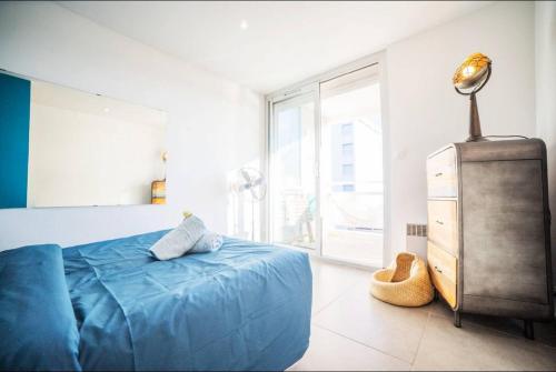 - une chambre avec un lit bleu et une commode dans l'établissement LE CALDERINI APPART - Face PLAGE WIFI et PARK Gratuit CALME - Résid Le Surcouf -TOP PROS SERVICESConciergerie La Grande Motte, à La Grande Motte