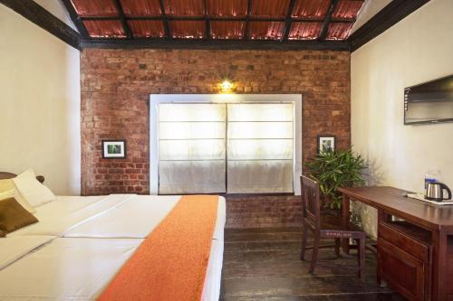 a bedroom with a bed and a desk and a window at Niyati - Boutique Stay in Cochin