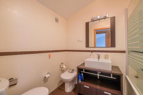 a bathroom with a sink and a toilet and a mirror at Ático-dúplex geniales vistas al mar in Vinarós