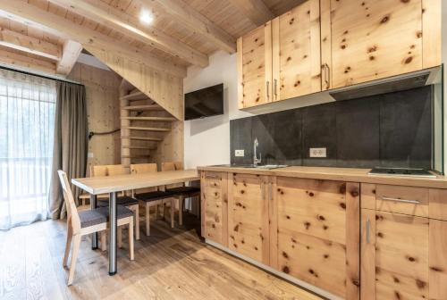 a kitchen with wooden cabinets and a table with chairs at Le Table E in San Vigilio Di Marebbe