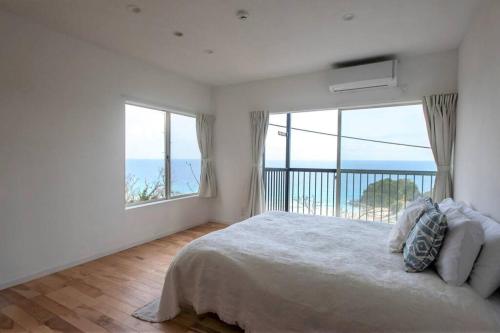 um quarto com uma cama grande e uma janela grande em Sirahama Beach House em Shimoda