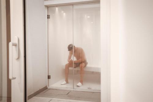 a man sitting on a bench in a glass wall at Mythical Villas Zeus and Venus in Protaras