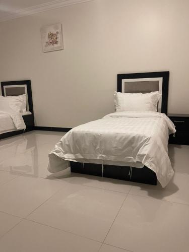 ein Schlafzimmer mit einem großen Bett mit weißer Bettwäsche und Kissen in der Unterkunft هوتيل حايل للشقق المفروشة يتوفر شهري سنوي in Ha'il