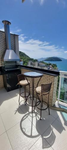 a patio with two chairs and a table on a balcony at Cobertura Duplex Vista Mar in Mangaratiba